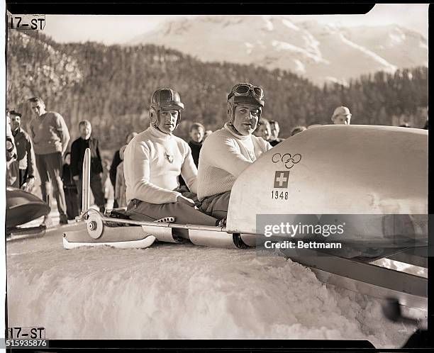 St.Moritz, Switzerland- These two dare-devils, members of the Swiss Olympic squad, relax in their sled after winning the Two-man bobsled event. They...