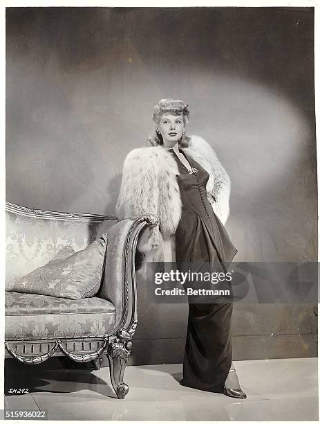 Hollywood, CA- Lovely Irene Manning, Warner Brother's actress, models this evening ensemble of peg-top skirted evening dress of black crepe. The...