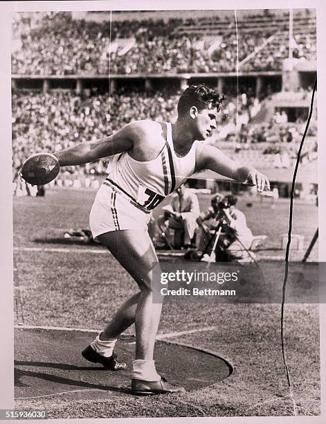 Berlin, Germany- A perfect model for a sculptor, Kenneth Carpenter of the United States is shown throwing the discus for the winning heave of 165...