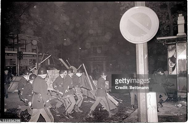 Paris, France- Helmeted gendarmes pass a barricade made of overturned electrical panel during street fighting in the Latin Quarter, in the early...