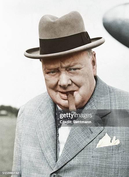 British statesman Winston Churchill in 1949, smoking one of his beloved cigars as he leaves the plane that brought him back from a continental...