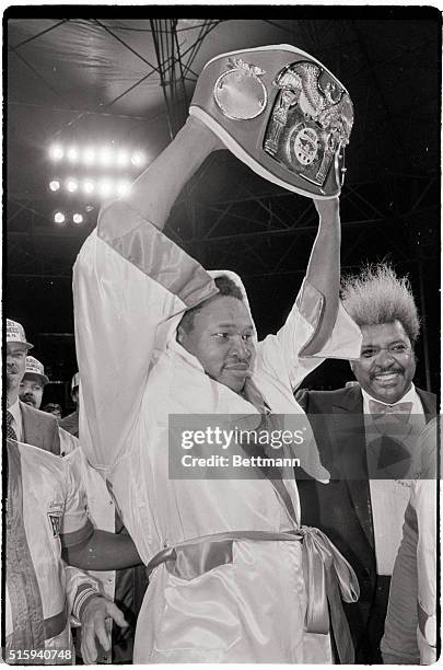 Boxing promoter Don King smiles as heavyweight champion Larry Holmes hold up his International Boxing Federation, or IBF, championship belt after...