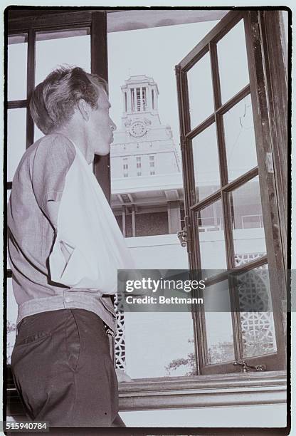 His wounded arm still in a sling, J.Scott Allen examines the window through which he was shot by sniper Charles Whitman at the University of Texas in...