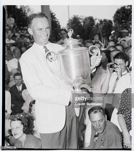 Golfer Denny Shute smiles as he holds the National PGA Championship trophy for winning the golf tournament for the second year in a row. Pittsburgh,...