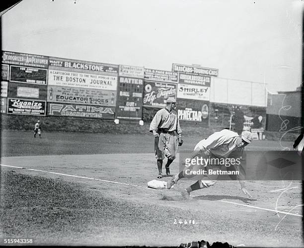 Tris Speaker of Boston Red Sox sliding past third base. St. Louis Brown fielder looks on.