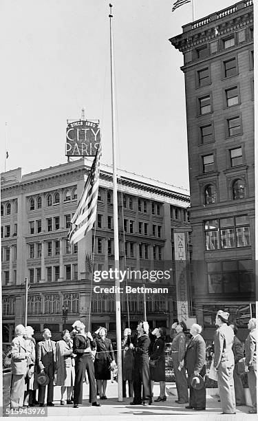 San Franciscans watch as sailors lower a flag to half-mast after the death of President Franklin Roosevelt.