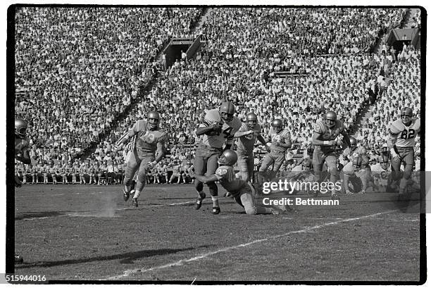 Bruin player tackles Ernie Davis of Syracuse during a 1959 game in the Los Angeles Coliseum.