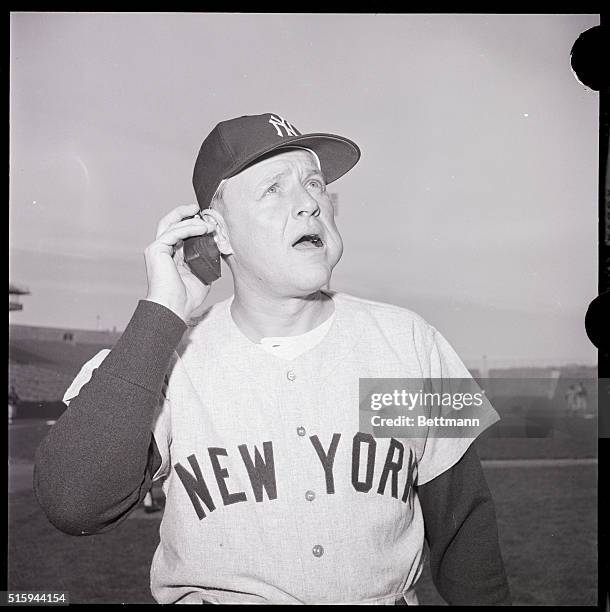 Manager of the New York Yankees listens to National League playoff game through a tiny radio. The winner of the game, either the San Francisco Giants...