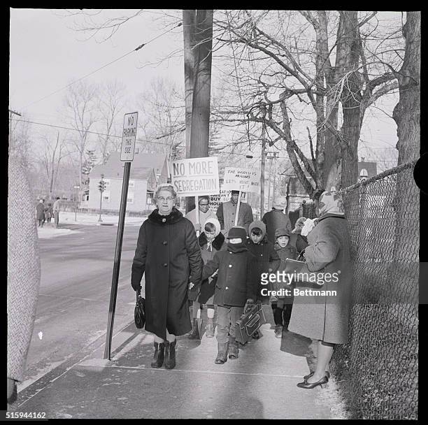 Grandmother leads grandchildren past a group of picketers protesting school segregation in Englewood, New Jersey.