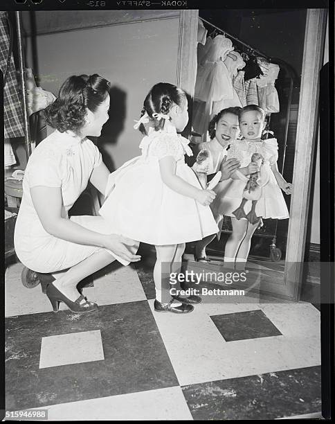 New York, NY: Mrs. Chang adjusts dress on her daughter Lorraine, 3 years old at the international Spring Fashions, Tavern on the Green, Central Park.