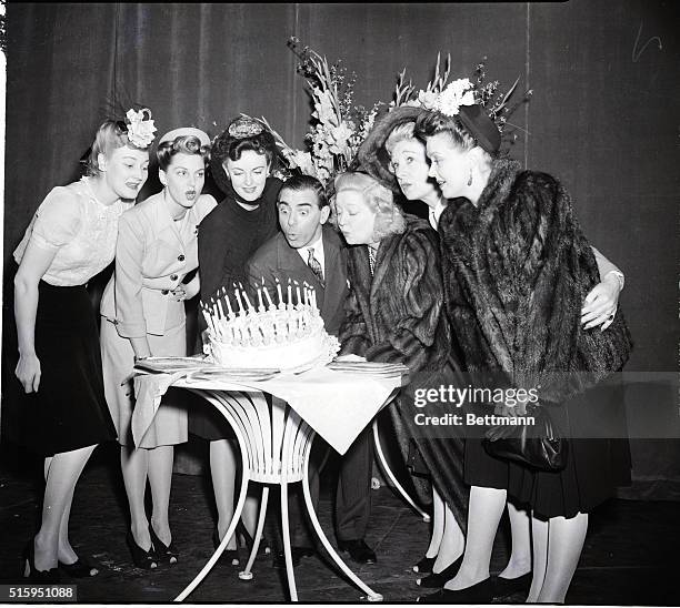 New York, New York: Assisted by stage figures of the past and the present who have been associated with him, comedian Eddie Cantor, center, blows out...