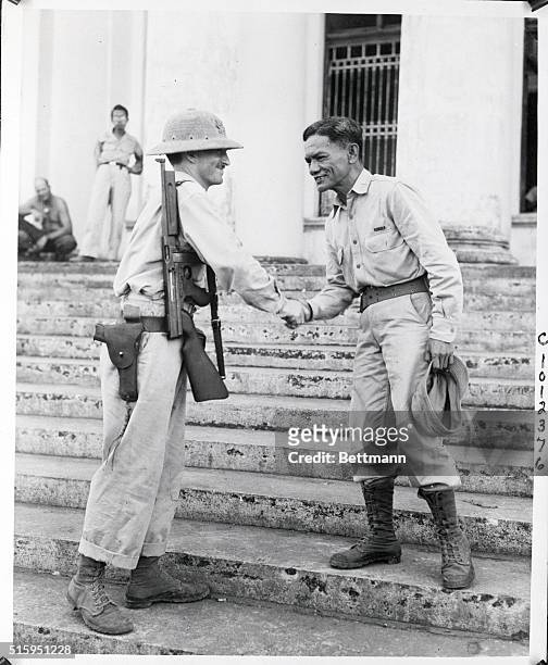 Leyte: Col. R.K. Kangleson, leader of Philippine guerilla forces congratulates Cliff D. Robertson one of his top assistants after merger with Gen....