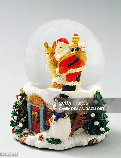 Santa Claus with toys, snowman and Christmas trees, snowglobe. 20th century.