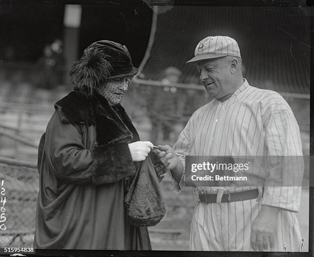 Mrs. Wilbert Robinson, wife of the genial manager of the Brooklyn Dodgers presenting him with a St. Joseph's medal as a lucky charm before the start...