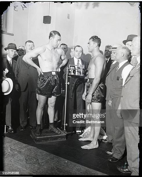 New York, NY- Casting the "evil eye" at Max Schmeling, Jack Sharkey stands on the scales during the official weigh-in at the State Building in New...