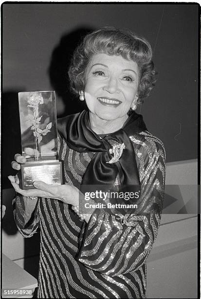 New York, NY- Academy Award Winning actress Claudette Colbert holds the Lord & Taylor 1983 Rose Award, which she received for her "extraordinary...