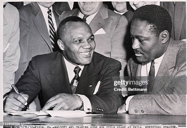 Philadelphia, PA- Jersey Joe Walcott and Ezzard Charles, the man he dethroned for the crown last July, sign a contract for a 15-round title bout,...