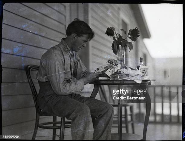 "Battling" Nelson, lightweight boxer, is shown seated at a table reading cards that wish him well.