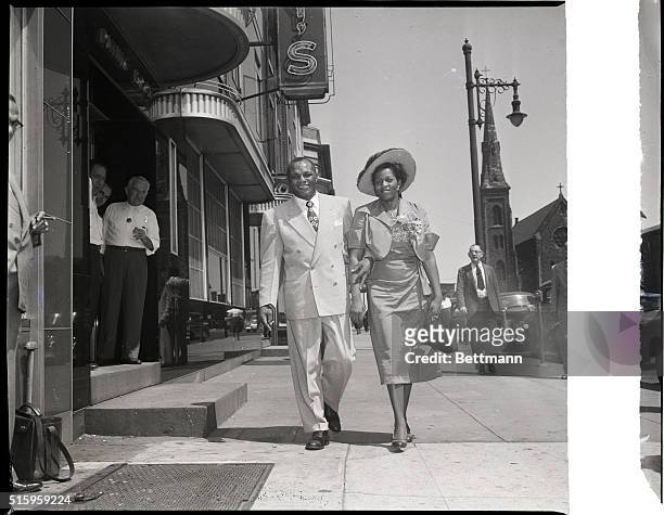 Camden, New Jersey- Heavyweight champ of the world, Jersey Joe Walcott, and his wife are snapped strolling down Camden's Main Street during one of...