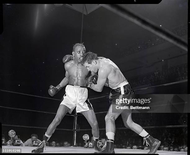 New York, NY- With mouth open, featherweight champ Sandy Saddler gets set to swing up with a right in close-quarter clash with Paddy DeMarco during...