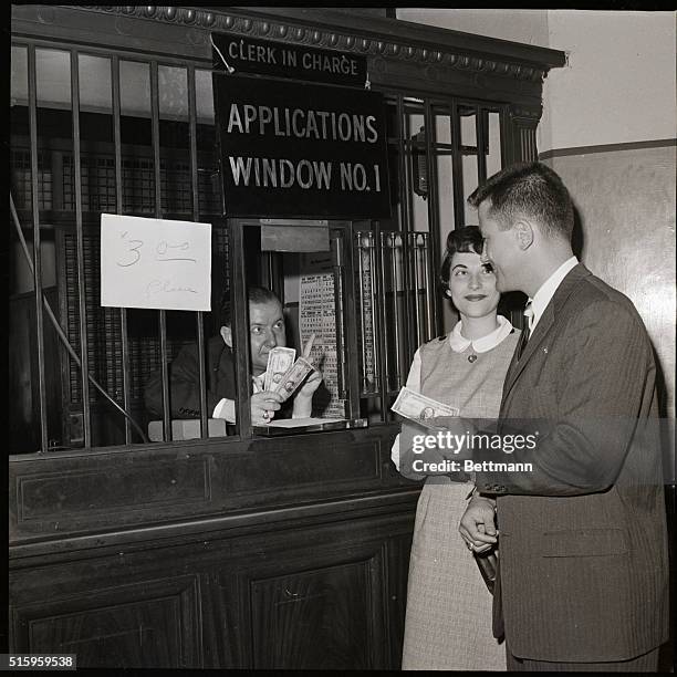 New York, New York- Asking for another dollar, clerk George Whitfield reminds prospective bridegroom William Aronson that the marriage license fee...