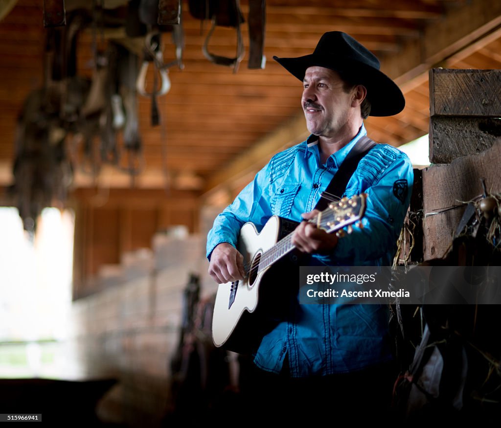 Country singer strums guitar inside cow shed