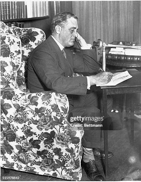 Franklin Delano Roosevelt sits in an armchair and speaks on the phone in his office.