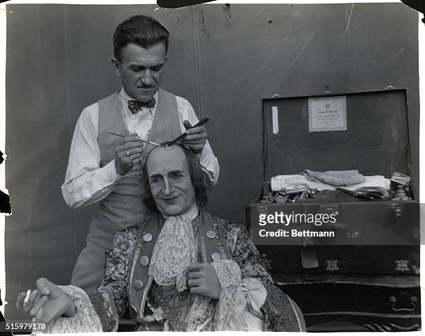 Jack L. Pierce, Hollywood's most prominent make-up artist, is here seen putting a "split curl" on the noble brow of none other than the popular...