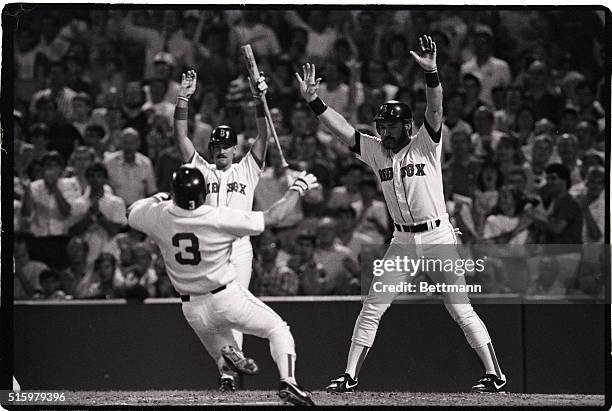 Boston, MA- Red Sox players Mike Greenwell and Wade Boggs raise arms as teammate Jody Reed slides safely across home plate during first inning action...