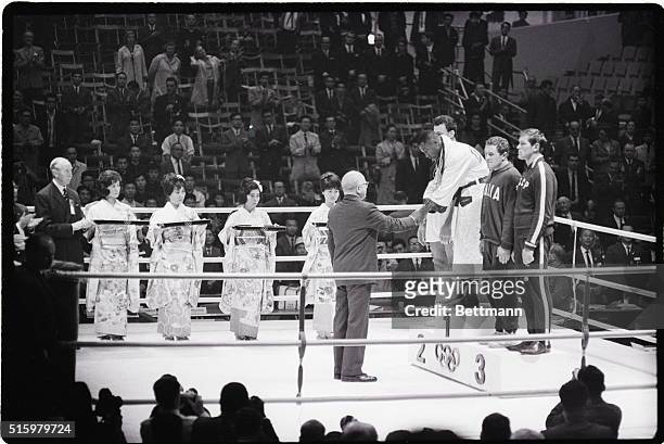 Tokyo, Japan- Joe Frazier of Philadelphia is shown shaking the hand of the official who has awarded the medals in the ring at an Olympics ceremony in...