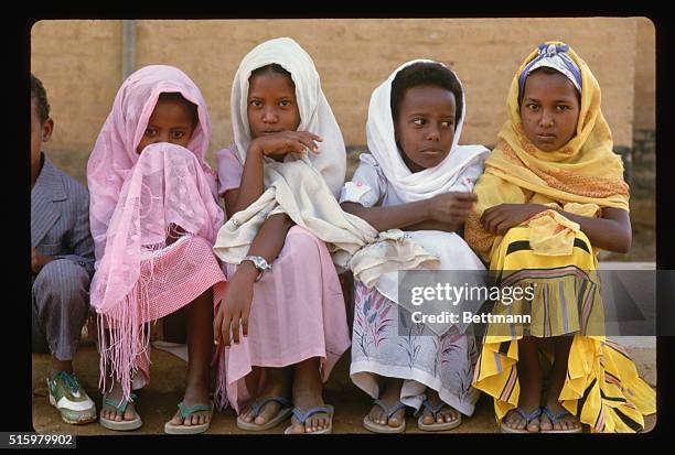 Outside of Kassala, Sudan A group of young girls sit on the edge of a road. They are dressed in bright colors and are members of an undisclosed...