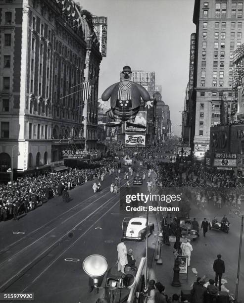 Photo shows the Macy's Thanksgiving Day Parade, 22nd November 1945. Attendants drag the huge 'Bobo The Hobo' balloon down the street as spectators...