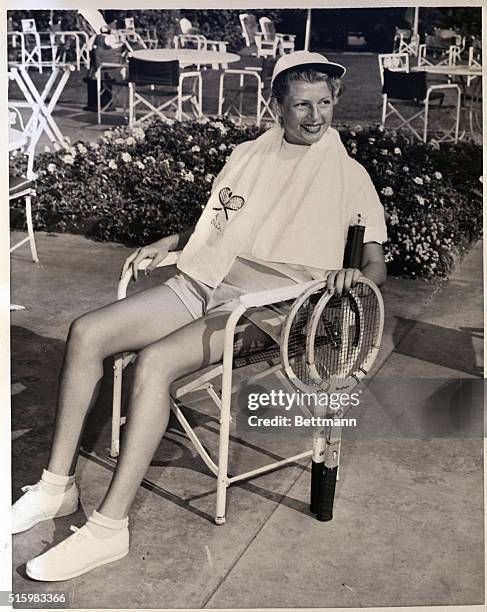 Beverly Hills, CA- Screen actress Rita Hayworth relaxes after a tennis match at the Beverly-Wilshire Hotel. The red-haired film beauty is still...