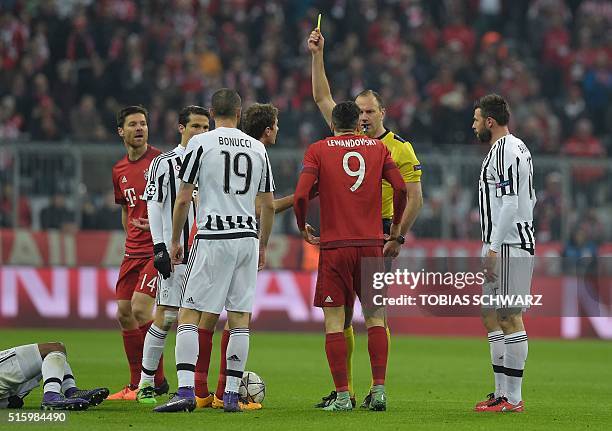 Swedish referee Jonas Eriksson shows a yellow card to Bayern Munich's Polish striker Robert Lewandowski during the UEFA Champions League, Round of...