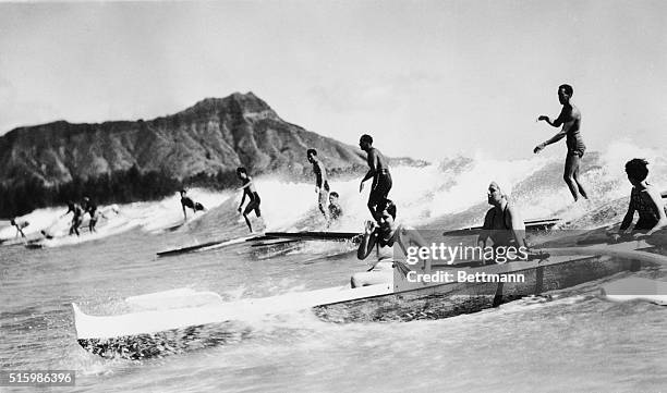 Honolulu, Hawaii. Outrigger canoe and surfers on wave, Waikiki Beach.