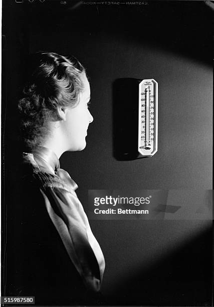 Photo shows a Fahrenheit thermometer. Miss Norma Douglas is shown looking at the thermometer.