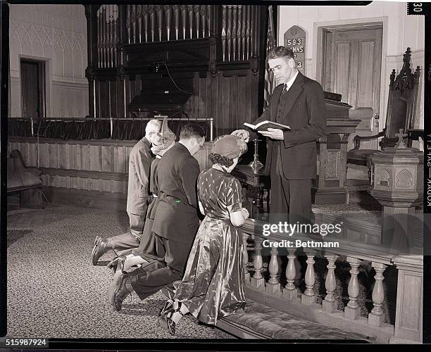 Potsdam , NY: Methodist Church induction ceremony. Photo shows two men and two women kneeling before a minister. Photograph, 1949.