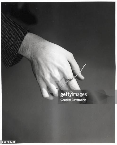 Hand with string tied on index finger, as one would do to remember something. Undated.