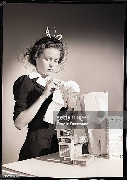Photo shows a girl shopper with a ration book. Model: Shirley Fletcher. Ca. 1940s.