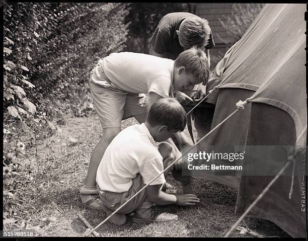 Photo shows three boys up to something with a canister, behind a tent. Models: Benton Snyder, William M. Connor, Jr., and Daniel B. Connor. Ca. 1950s.