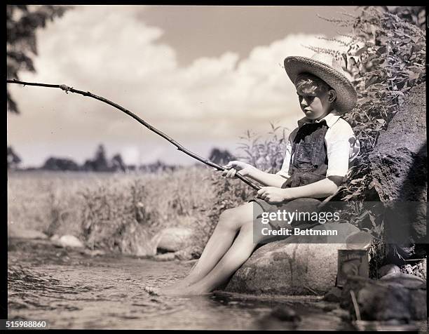 A young boy fishes in a stream, with a makeshift fishing pole. He is  News Photo - Getty Images