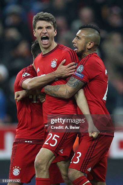 Thomas Mueller of Bayern Muenchen celebrates his first goal with teammates Juan Bernat and Arturo Vidal during the Champions League round of 16...