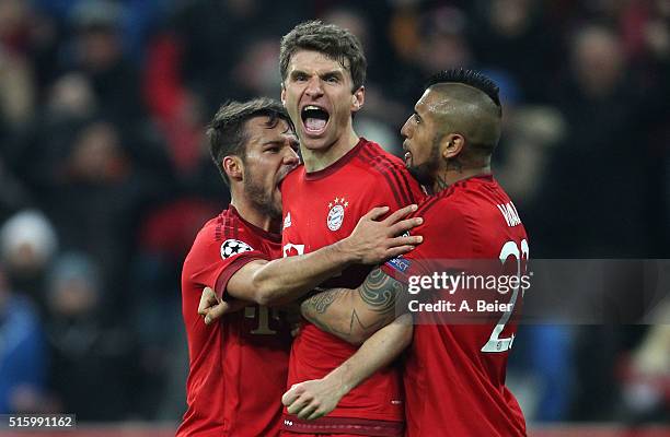 Thomas Mueller of Bayern Muenchen celebrates his first goal with teammates Juan Bernat and Arturo Vidal during the Champions League round of 16...