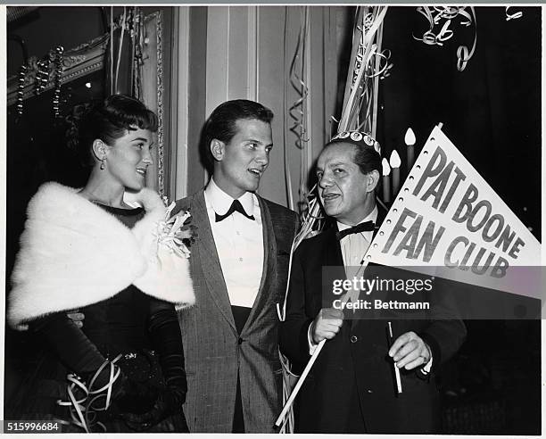 Pat Boone with a man and a woman. The man holds a "Pat Boone Fan Club" pennant. Undated photograph.