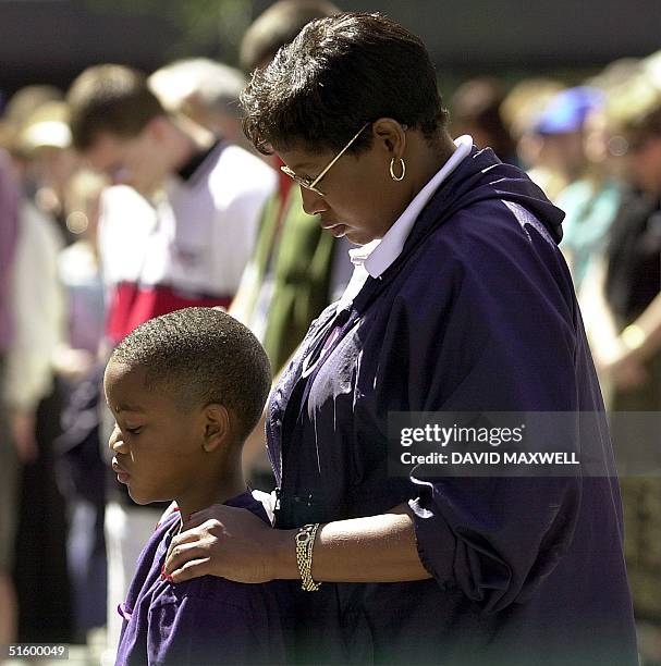 Crystal Brown and her son Demitri Brown bow their heads during a gathering to pray for peace on 13 April, 2001 at Fountain Square in downtown...