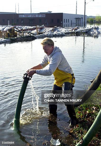 Ron Kindelsperger places a pump hose into floodwater surrounding Mid America Glass in Davenport, Iowa as he attempts to protect company property 25...