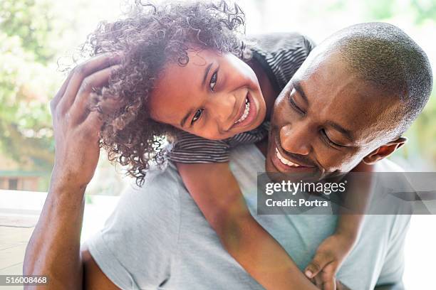 happy girl with arms around father at home - african american girl child stock pictures, royalty-free photos & images