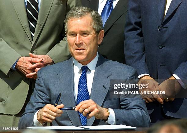 President George W. Bush smiles after signing an executive order to preserve Social Security for senior Americans while building wealth for younger...