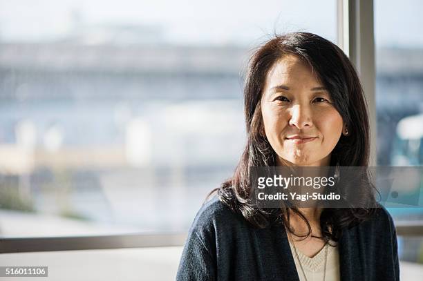 businesswoman standing in the office of the window - japanese woman stock pictures, royalty-free photos & images