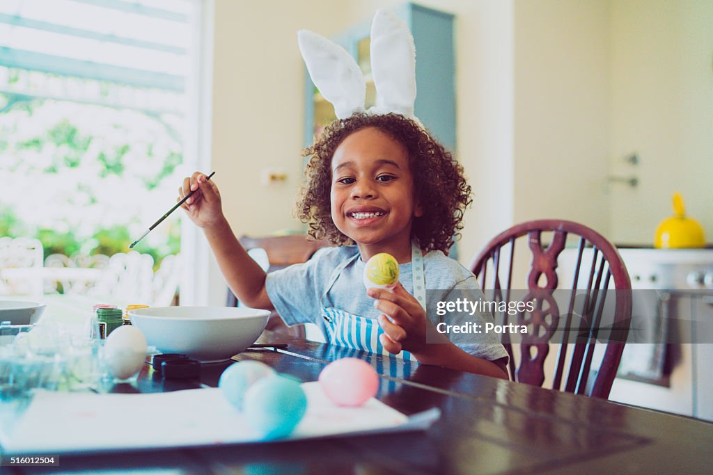 Happy boy coloring Easter egg at home